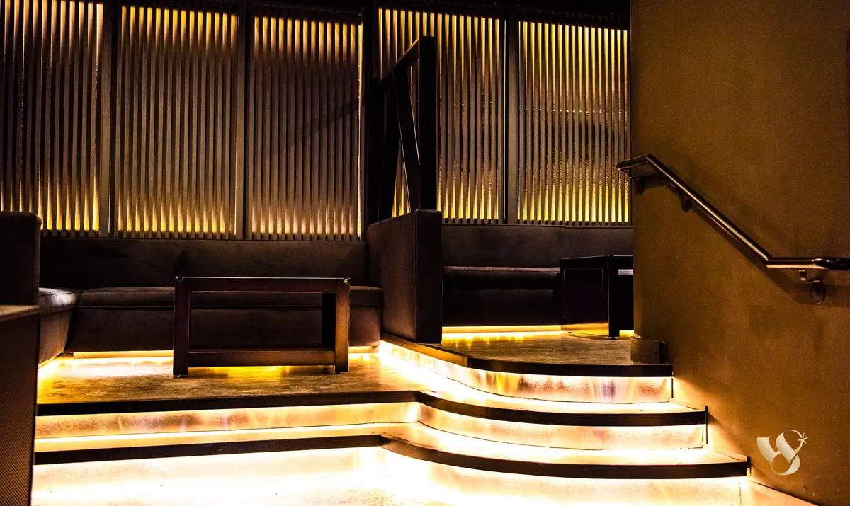 Terraced VIP seating at West 8 with gold under-lit steps and slat walls